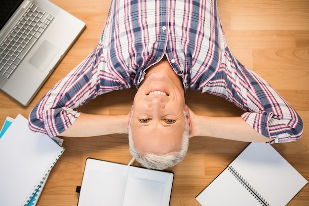 Photo smiling man lying on floor surrounded by office items