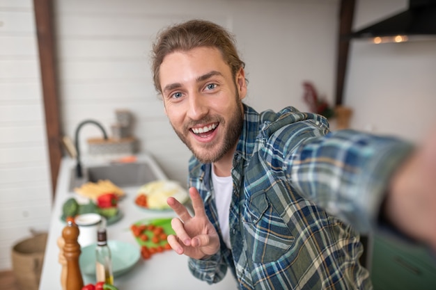 キッチンで自分撮りをしている笑顔の男