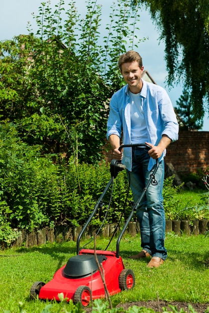 Smiling man mowing the grass in the sun