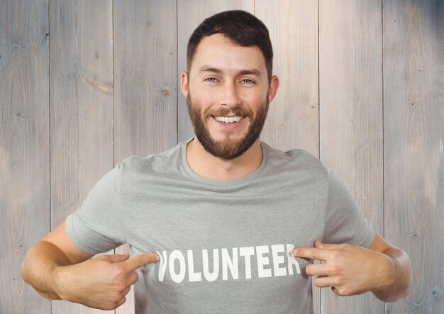 Foto uomo sorridente che indica il titolo di volontario sulla sua maglietta