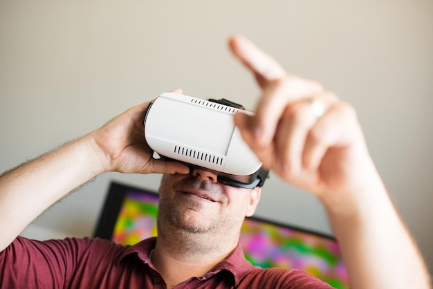 Smiling man pointing white using virtual reality simulator at home