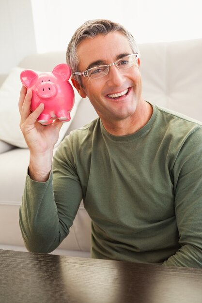 Smiling man posing with a piggy bank