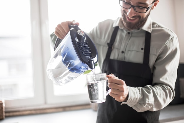 Smiling man pouring clean water into a glass