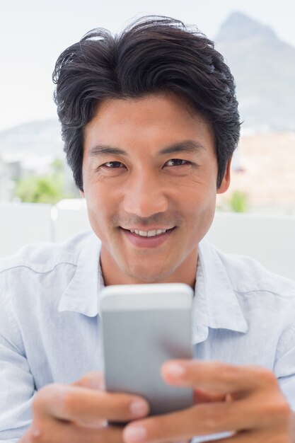 Smiling man sending a text message