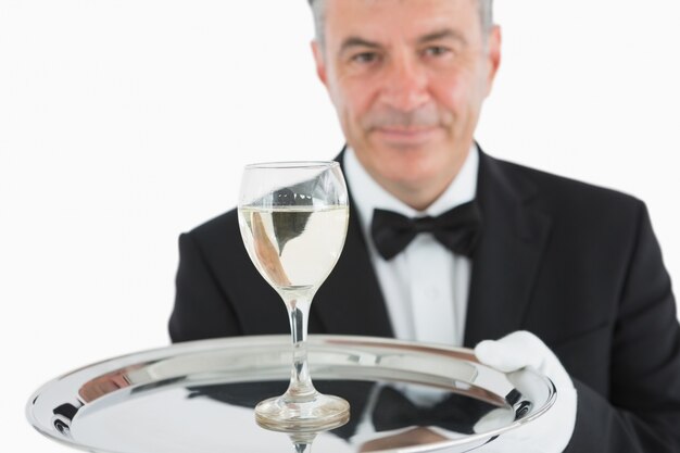 Smiling man serving glass of wine on platter