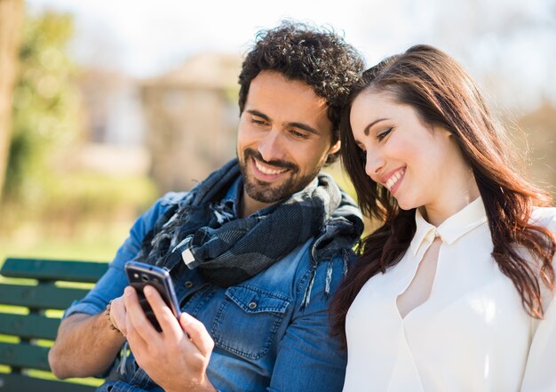 Uomo sorridente che mostra il suo telefono cellulare ad una ragazza