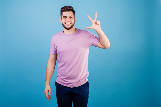 Smiling man showing three fingers isolated on blue