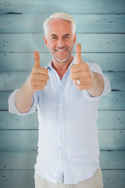 Smiling man showing thumbs up to camera against wooden planks