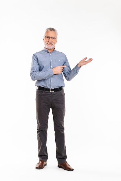 Smiling man showing with hands at copy space isolated