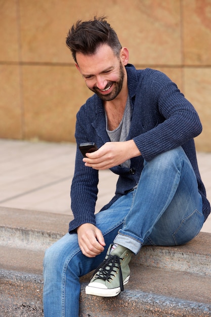 Smiling man on sidewalk using mobile phone