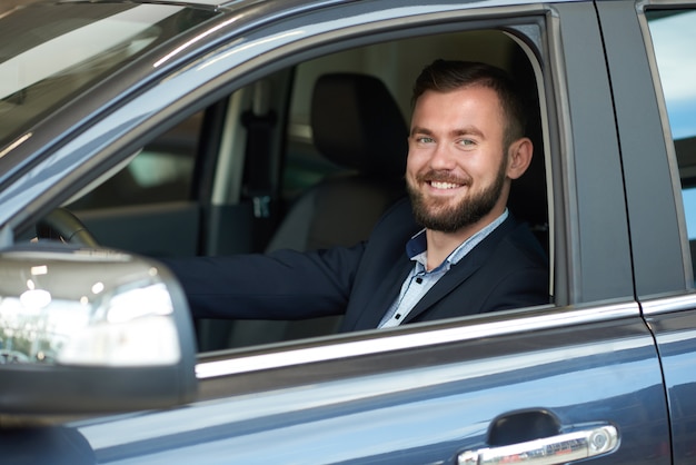 カメラを見て、車のキャビンに座っている男の笑みを浮かべてください。