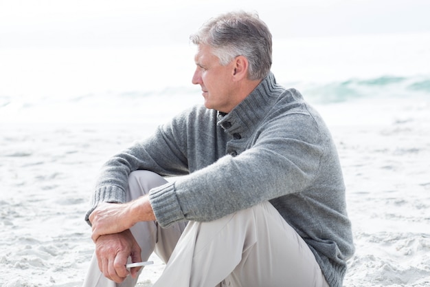 Smiling man sitting down in the sand