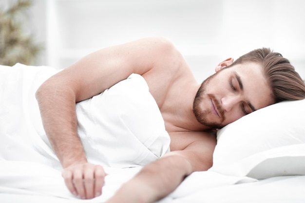 Smiling man sleeping on a comfortable bed