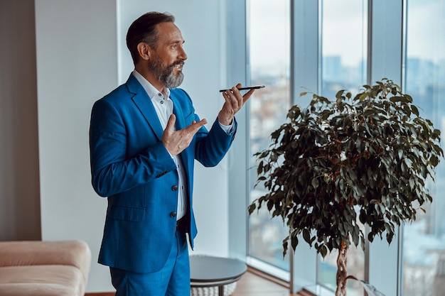 Smiling man standing in front of the window and talking on phone