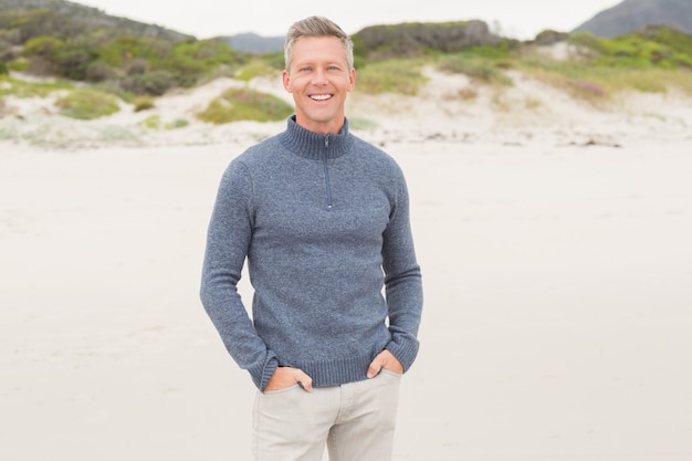 smiling man standing with hands in his pockets