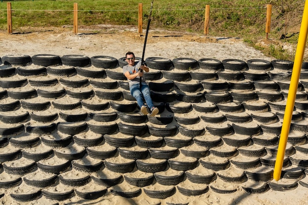 Smiling man in sunglasses riding on a swing