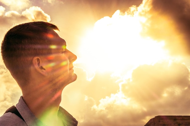 Smiling man in sunlight rays Handsome man against golden sky Blessing concept Heaven background