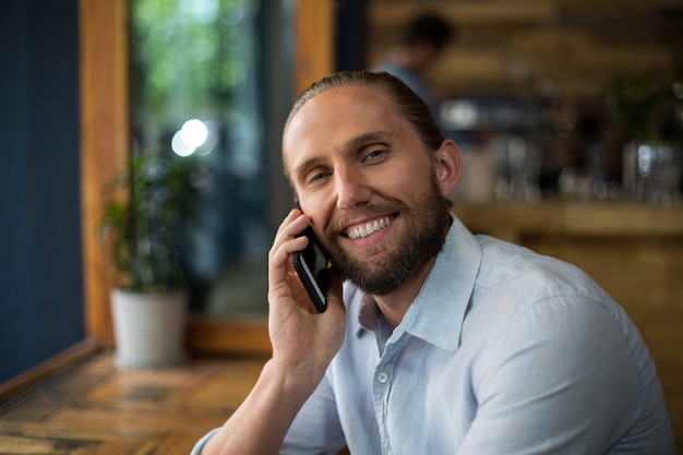 Smiling man talking on mobile phone at coffee