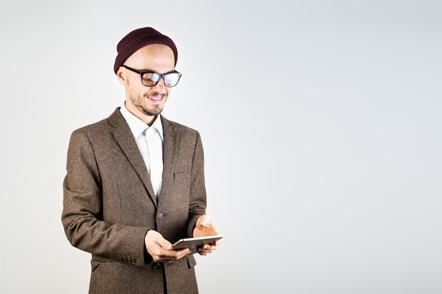 Smiling man in tweed jacket with a tablet computer. Male person in hipster style clothing uses technology, studio shot in white background