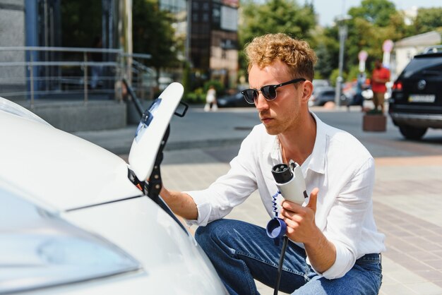 車から充電器を抜く笑顔の男