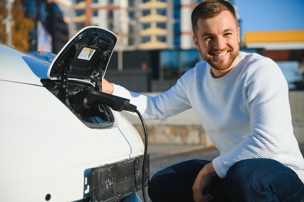 車から充電器を抜く笑顔の男