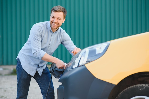 Uomo sorridente che scollega il caricabatterie dall'auto