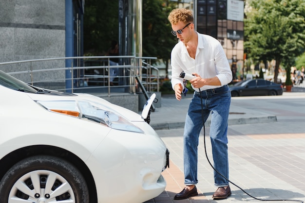 写真 車から充電器を抜く笑顔の男