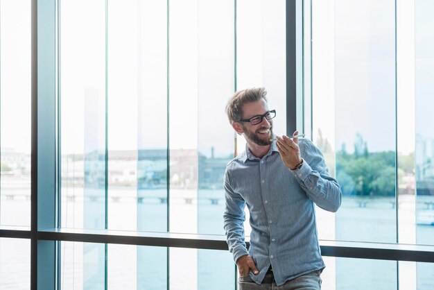 Smiling man using cell phone at the window