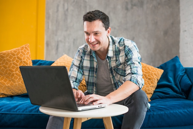 Smiling man using laptop at home