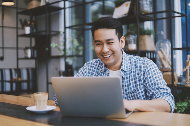 Smiling man using laptop while sitting in cafe