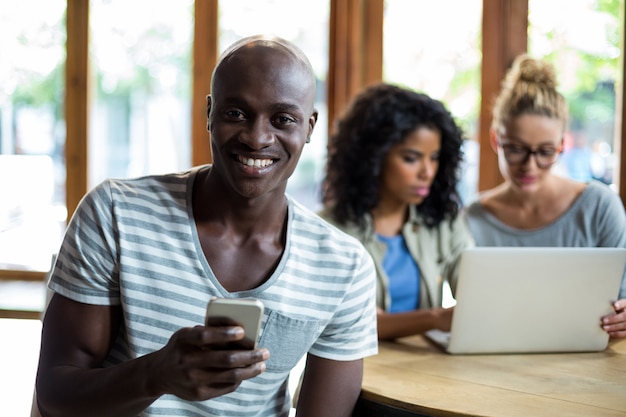 Smiling man using mobile phone in coffee