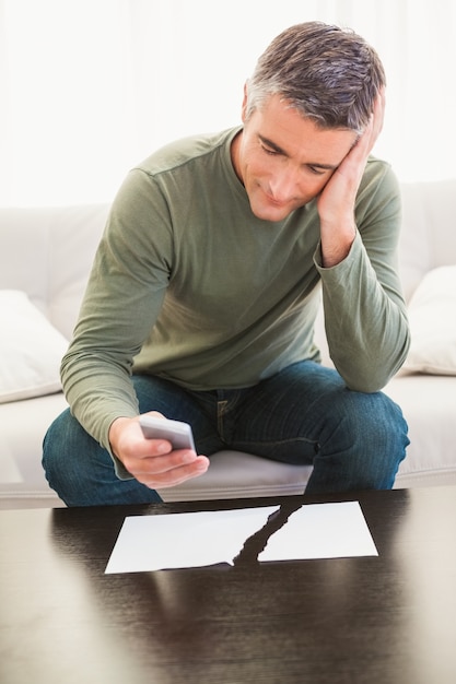 裂いた紙の近くで携帯電話を使って笑っている男