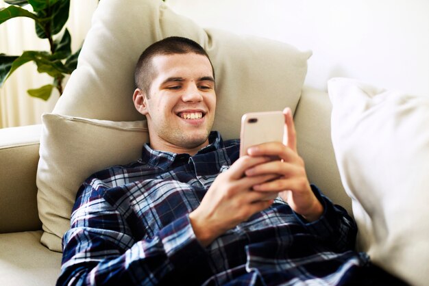 Smiling man using a smartphone at home