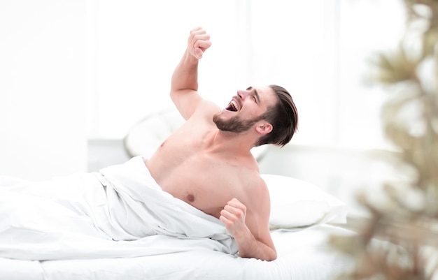 Uomo sorridente che si sveglia in un'accogliente camera da letto