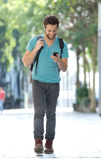 휴대 전화 및 가방 도시에서 걷는 웃는 남자