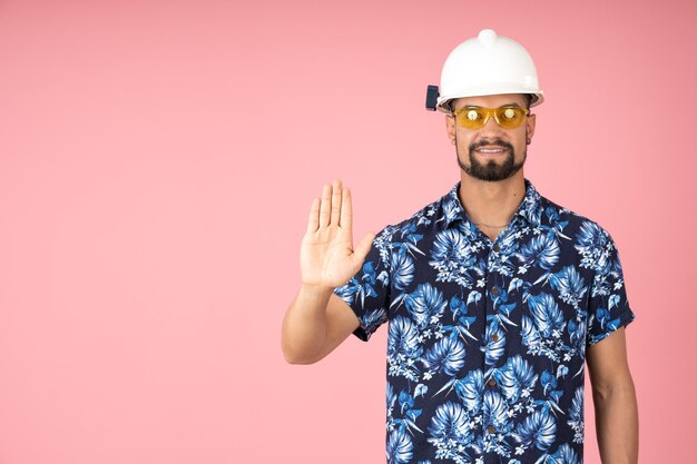 Smiling man wearing a helmet and pointing to stop with his hand