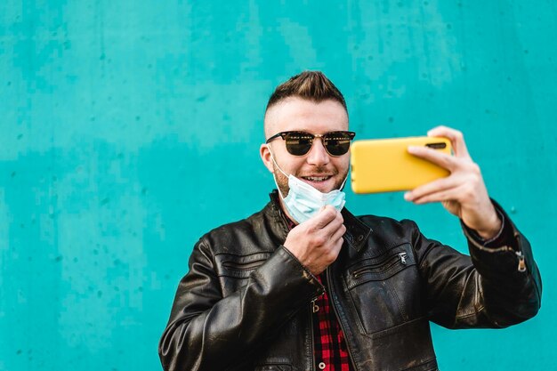 Smiling man wearing mask doing selfie against wall