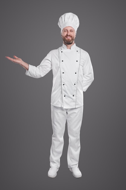 Smiling man in white chef uniform pointing aside