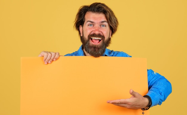 Smiling man with advertising banner. Bearded male with empty sign board. Space for text. Advertising. Black friday. Sale and discount. Season sales.