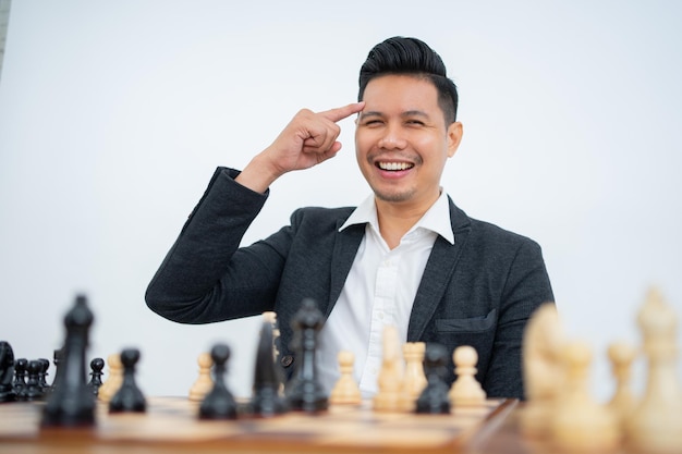 체스를 하는 동안 머리를 가리키는 손가락으로 웃는 남자