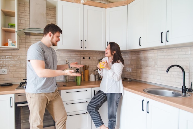 Smiling man with woman at kitchen drinking tea