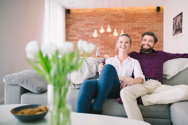 Smiling man and woman sitting on couch