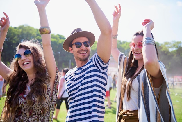 smiling man and women dancing on grass against sky