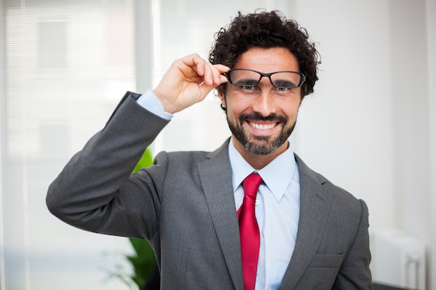 Smiling manager in his office holding his eyeglasses