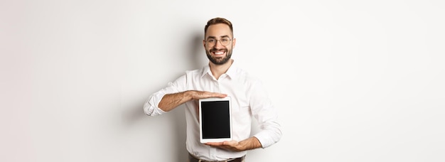 Smiling manager showing something on digital tablet screen demonstrating website standing over white