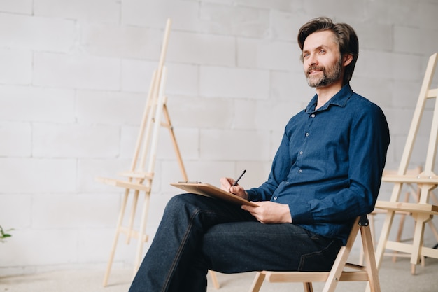 Smiling Mature Artist Drawing Sketches in Studio