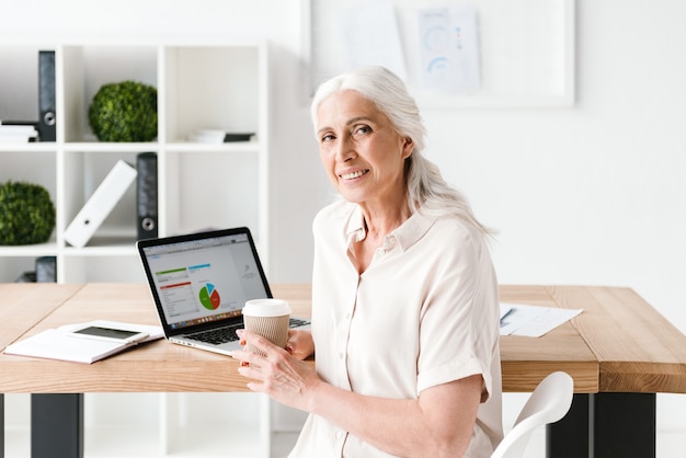 Smiling mature business woman working on laptop