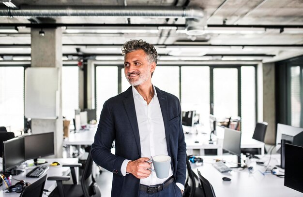 Smiling mature businessman with coffee mug in office