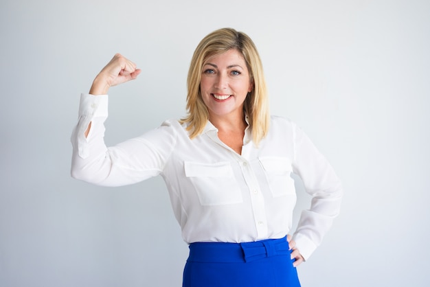 Smiling mature Caucasian woman in formal blouse flexing bicep.