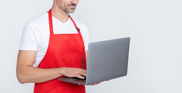 Smiling mature man in apron chatting on computer